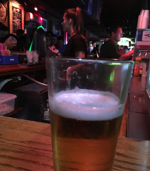 photo of beer pint on the bar with bartenders in the background