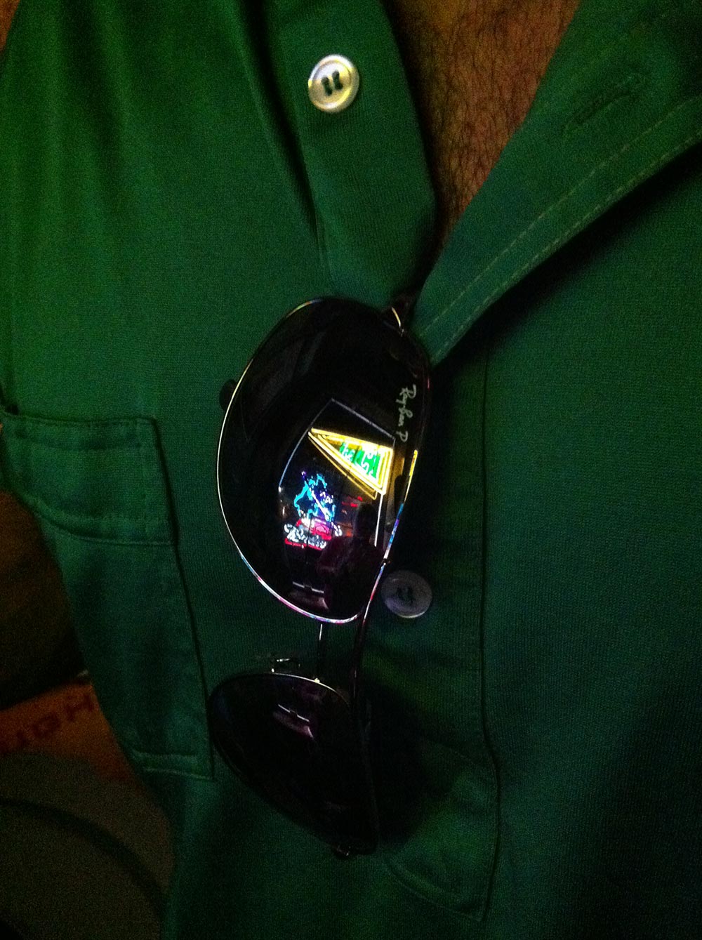 photo of guy in green shirt with CI neon reflected in sunglasses